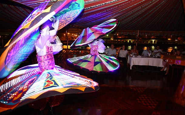 Crew serving guests on the open deck with Dubai Marina skyline at night