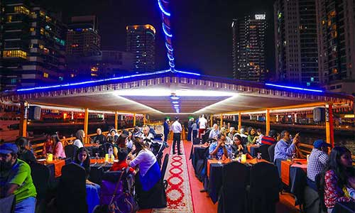 Dinner cruise dhow passing Ain Dubai observation wheel at dusk