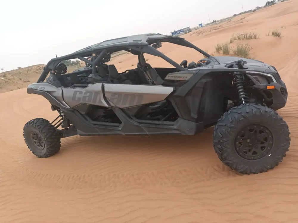 A four-seat off-road buggy with large tyres parked on a Dubai desert dune