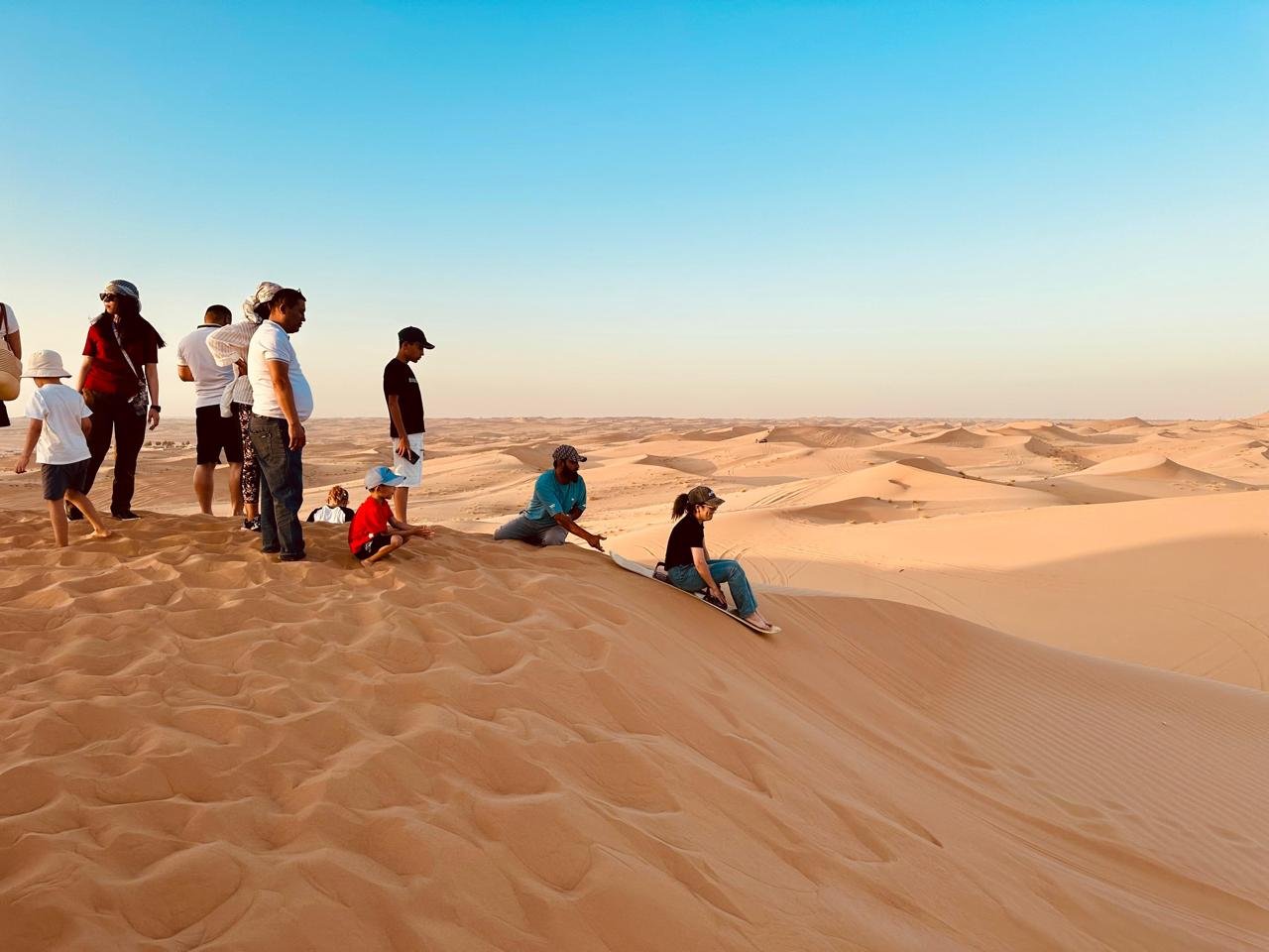 Sandboarding down the red dunes on a Red Dunes Desert Safari Dubai excursion